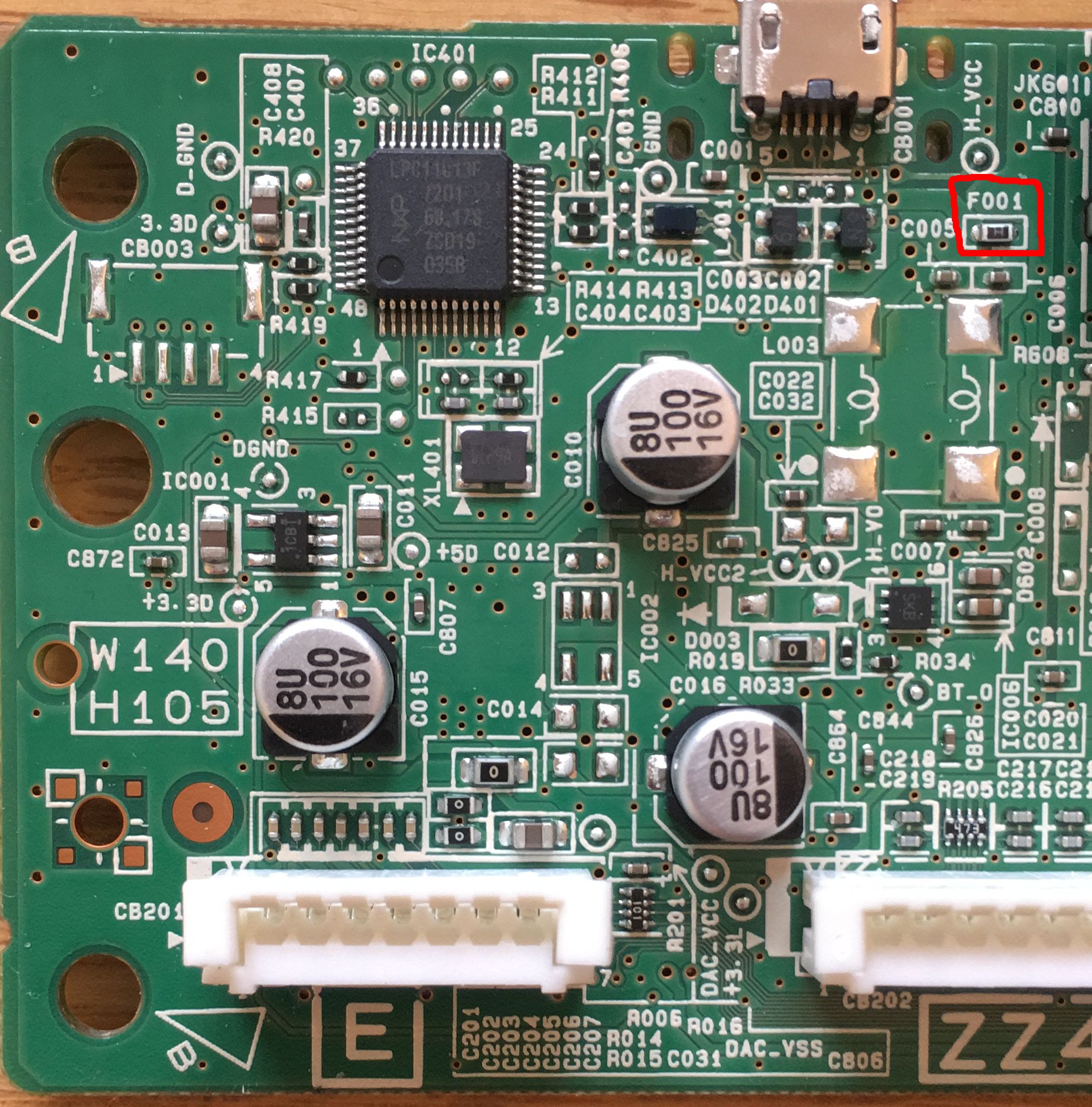 A photo of the circuit board with component F001 circled (near the unpopulated twin inductors)