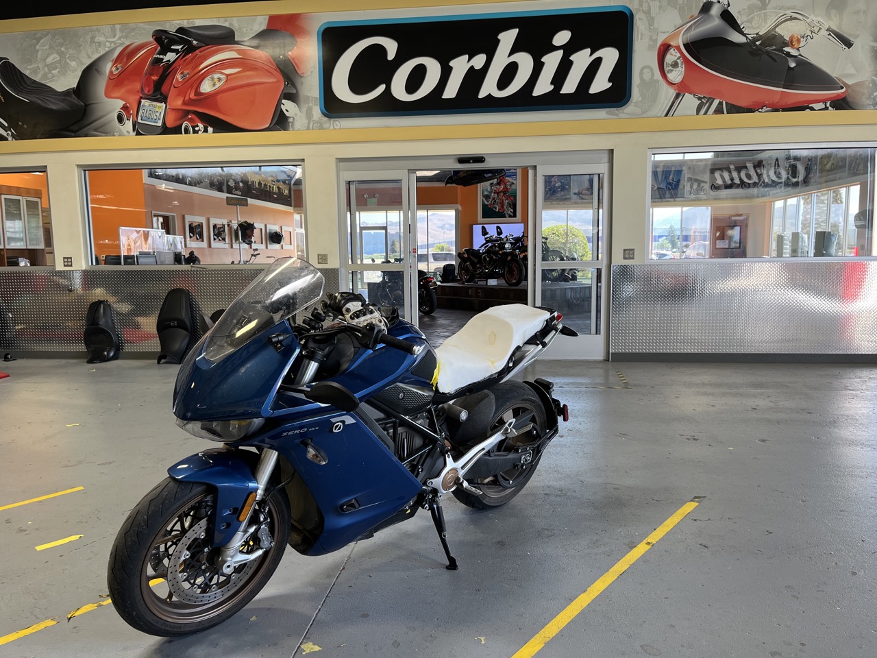 my Zero SR/S, with a raw foam seat, parked under the Corbin banner in their ride-in service area